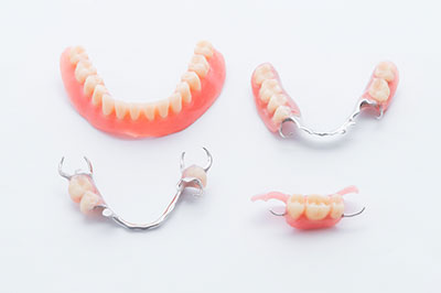The image displays a collection of dental appliances, including braces and retainers, arranged in two rows on a white background.