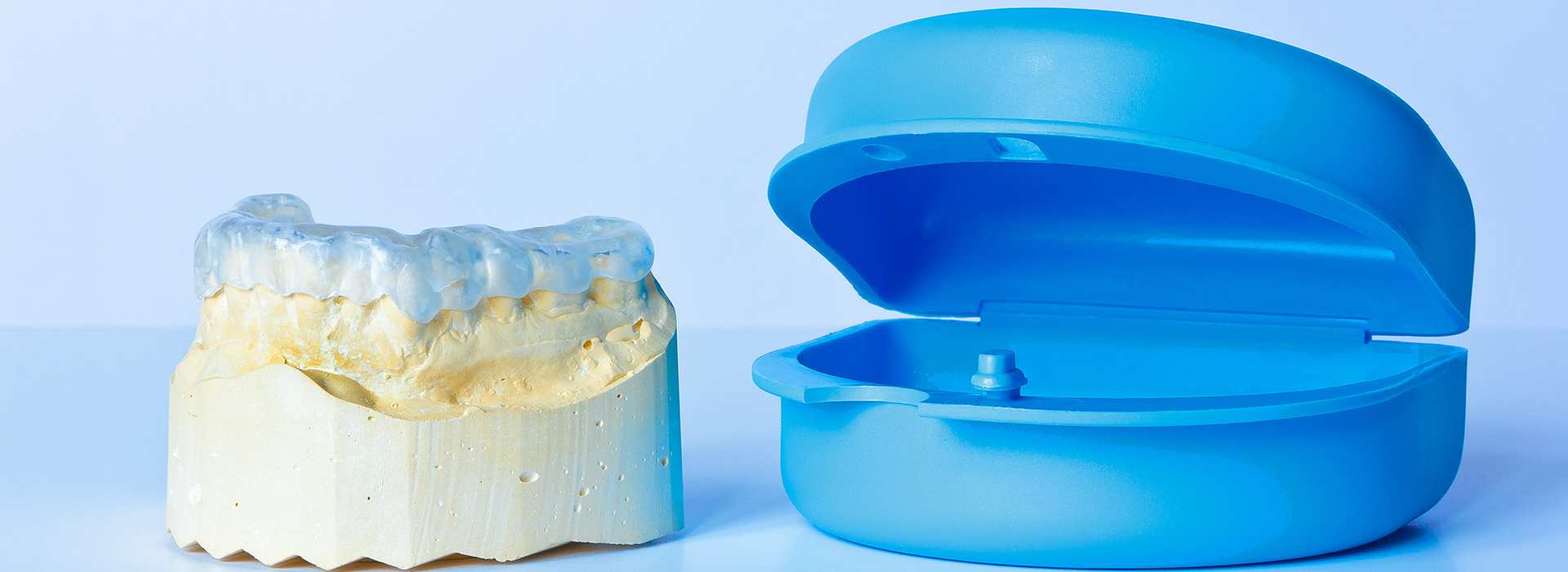 Dental implant components displayed side by side, including a blue surgical guide and a yellow abutment.