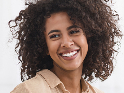 A woman with curly hair, smiling and looking directly at the camera.